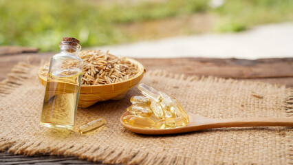 Capsule rice barn oil in wooden spoon with cold press rice barn oil. Rich in good fats, vitamin E,...