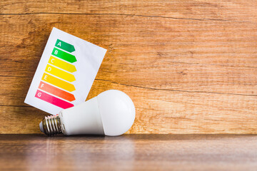Energy saving light bulb and energy label. Led Lightbulb on wooden table.