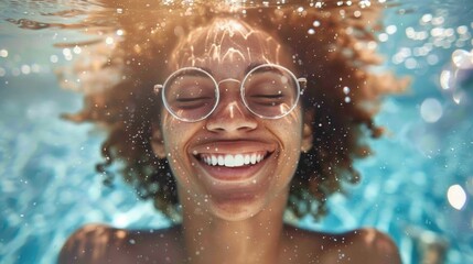 Fototapeta premium A young woman with glasses smiles joyfully underwater in a warm ocean setting