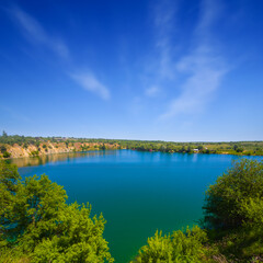 emerald lake with rocky coast under a cloudy sky