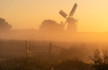 Colorful sunrise at a traditional windmill in the dutch countryside.