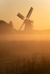 Colorful sunrise at a traditional windmill in the dutch countryside.