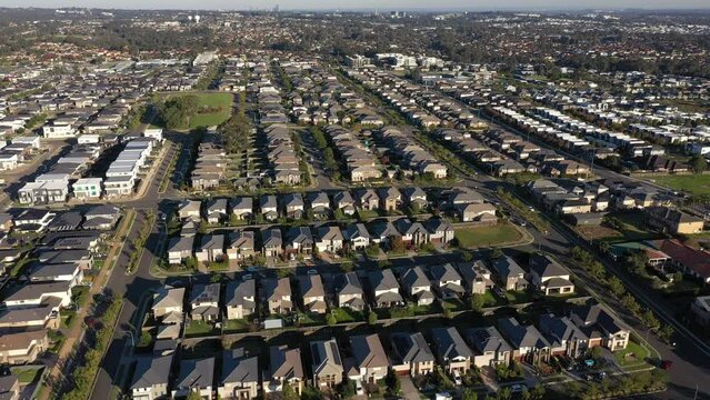Aerial flyover wide view in the late afternoon of similar sized modern brick veneer houses in outer north west Sydney, Australia.