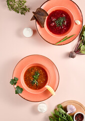 Assorted traditional Russian soups - borscht and solyanka, served in coral bowls for a heartwarming homemade meal