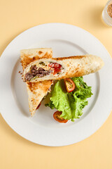 Toasty beef shawarma sandwich with vibrant lettuce and tomato, top view. Ideal for food catalogues and menu design