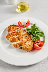 Golden crusted chicken fillet with cheese on a bed of lettuce, topped with cherry tomatoes, ideal for recipes and menu designs