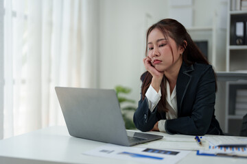 Fototapeta premium A businesswoman who is tired, stressed, and sore from working for a long time. After waiting for news Unsuccessful business approval results on laptop in office. Startup time concept, office syndrome