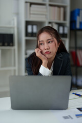 A businesswoman who is tired, stressed, and sore from working for a long time. After waiting for news Unsuccessful business approval results on laptop in office. Startup time concept, office syndrome