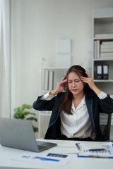 A businesswoman who is tired, stressed, and sore from working for a long time. After waiting for news Unsuccessful business approval results on laptop in office. Startup time concept, office syndrome