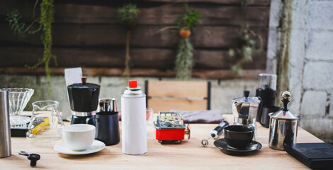 small business showcases portable coffee making equipment, including a moka pot on a gas burner, stainless steel accessories, and fresh coffee beans, all set on a rustic table.