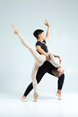 Dance Ideas. Sensual International Sportive Couple of Asian Man and Caucasian Woman Performing As Ballet Dancers On Grey in Studio During Suppots As Classical Dance © danmorgan12