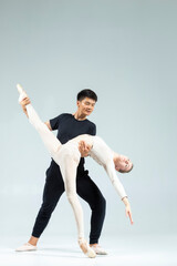 Sportive Couple of Asian Man and Caucasian Woman Performing As Ballet Dancers On Grey in Studio During Suppots As Classical Dance And Choreography. © danmorgan12