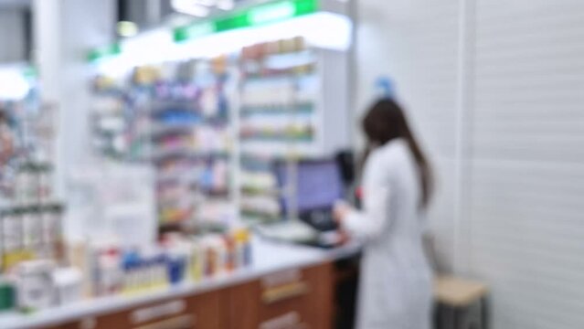 Blurred view inside of pharmacy with female pharmacist at workplace reading medicine prescription. Healthcare and cosmetics industry defocused background 