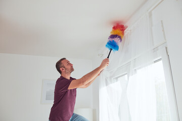 Man cleaning apartment with dusting broom.