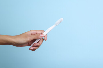 Hand Holding White Toothbrush Isolated On Light Blue Background
