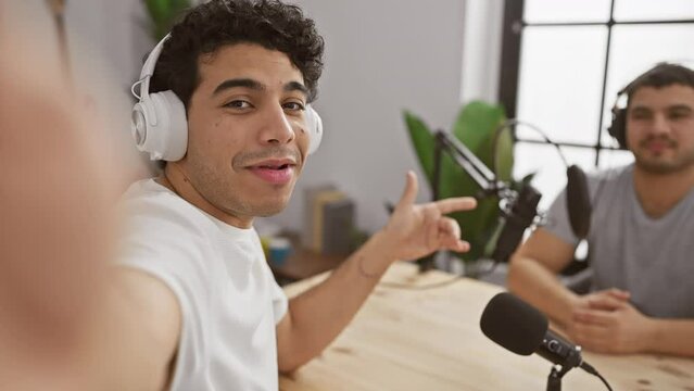 Two men podcasting in an indoor studio set with microphones and headphones, engaging in a discussion.