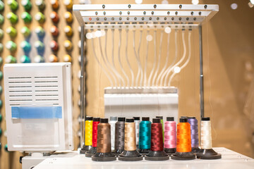 Selective focus to colorful sewing threads with blurry industrial sewing machine in a sewing shop....