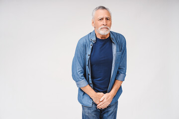 Portrait of mature gray-haired man with urologic disease posing on white background
