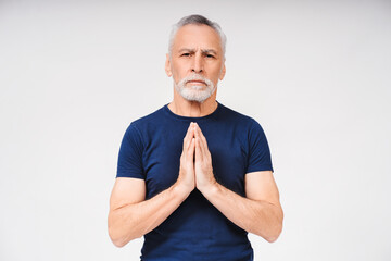 Close up portrait of gray-haired mature man praying over white background. Advertisement concept
