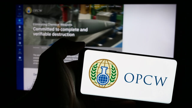 Stuttgart, Germany - 05-22-2024: Person holding mobile phone with logo of Organisation for the Prohibition of Chemical Weapons (OPCW) in front of web page. Focus on phone display.