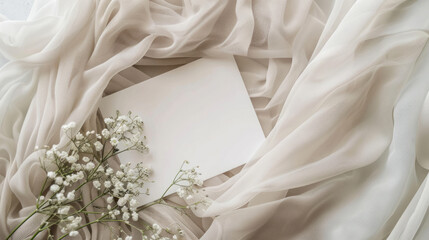 A blank white card rests on soft fabric, accompanied by delicate baby's breath flowers, serving as a web banner with room for text.