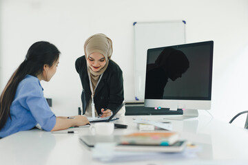 Two professional women discuss and analyze financial data and marketing strategies, presenting and brainstorming to increase company profits.