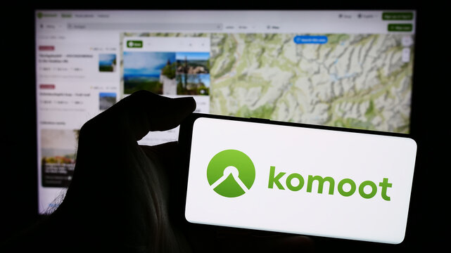Stuttgart, Germany - 05-23-2024: Person holding mobile phone with logo of German route planning app company komoot GmbH in front of business web page. Focus on phone display.