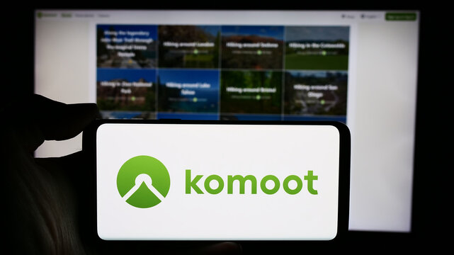 Stuttgart, Germany - 05-23-2024: Person holding cellphone with logo of German route planning app company komoot GmbH in front of business webpage. Focus on phone display.
