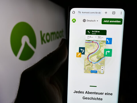 Stuttgart, Germany - 05-23-2024: Person holding mobile phone with web page of German route planning app company komoot GmbH in front of logo. Focus on center of phone display.