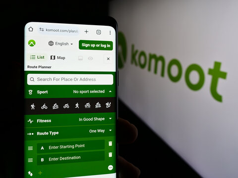 Stuttgart, Germany - 05-23-2024: Person holding smartphone with webpage of German route planning app company komoot GmbH in front of logo. Focus on center of phone display.