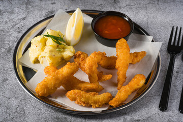 Deep fried shrimp tempura with potato salad on a metal plate