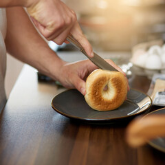 Hands, knife and bread in kitchen for breakfast in home with diet, wellness and nutrition in...