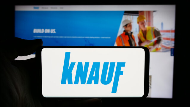 Stuttgart, Germany - 05-23-2024: Person holding cellphone with logo of German building materials company Knauf Gips KG in front of business webpage. Focus on phone display.