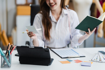 Fototapeta premium A young Asian businesswoman efficiently manages SMEs, utilizing her desk, tablet, laptop to handle online orders and live streams, showcasing entrepreneurial prowess in the dynamic market landscape.