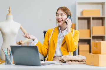 A young Asian businesswoman efficiently manages SMEs, utilizing her desk, tablet, laptop to handle...