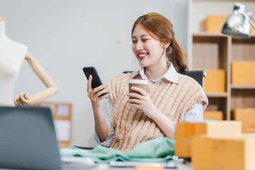 A young Asian businesswoman efficiently manages SMEs, utilizing her desk, tablet, laptop to handle...