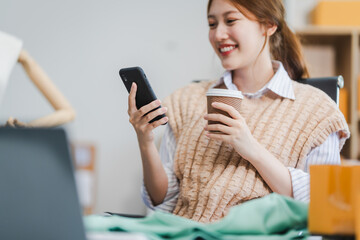 A young Asian businesswoman efficiently manages SMEs, utilizing her desk, tablet, laptop to handle...