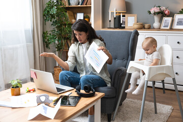 Young single divorced mother with baby using laptop computer for video call with her lawyer,...