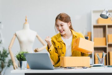 A young Asian businesswoman efficiently manages SMEs, utilizing her desk, tablet, laptop to handle...