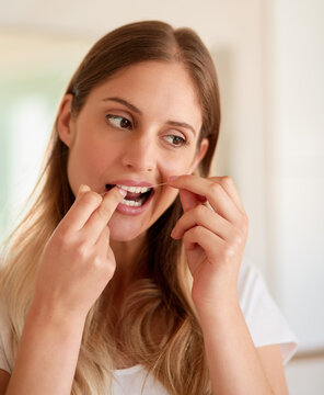 Morning, woman and floss teeth in bathroom for dental care or bad breath, cavities and prevent gingivitis gum disease or periodontitis. Girl, oral hygiene and cleaning mouth for plaque and healthcare