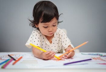 toddler baby playing and training to drawing with colored pencil on table