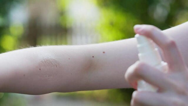 Slow motion of a person spraying arm with a tick prevention spray. Using an anti tick spray during the summer time to decrease the risk of tick bites.