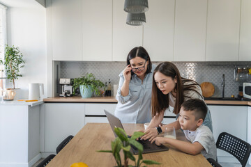 Happy Asian family using a laptop on the kitchen