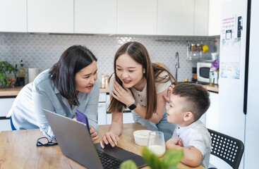 Happy Asian family using a laptop on the kitchen