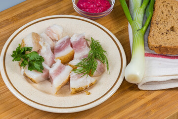 Salted pork fatback slices, bread and seasonings on cutting board