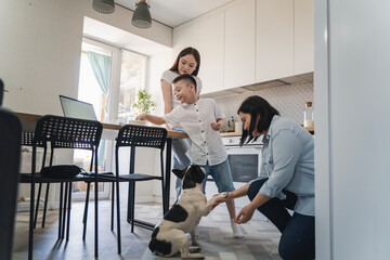 Happy Asian family playing with their cute dog in the kitchen.