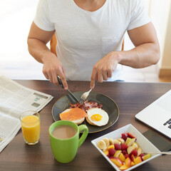 Hands, plate and eating breakfast in home with eggs, bread and bacon for wellness with diet. Person, knife and fork for food, natural protein and coffee in dining room, start or morning at apartment