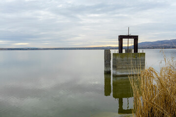 Remains of the irrigation system sluice in the lake. Reflection of clouds in water.