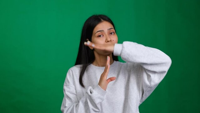 Time out gesture. Woman in a studio shot showing a hand sign for break or pause, indicating the need to stop or take a timeout as a deadline approaches