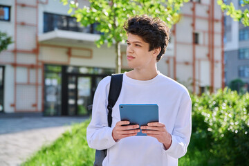 Young guy college student using digital tablet outdoor